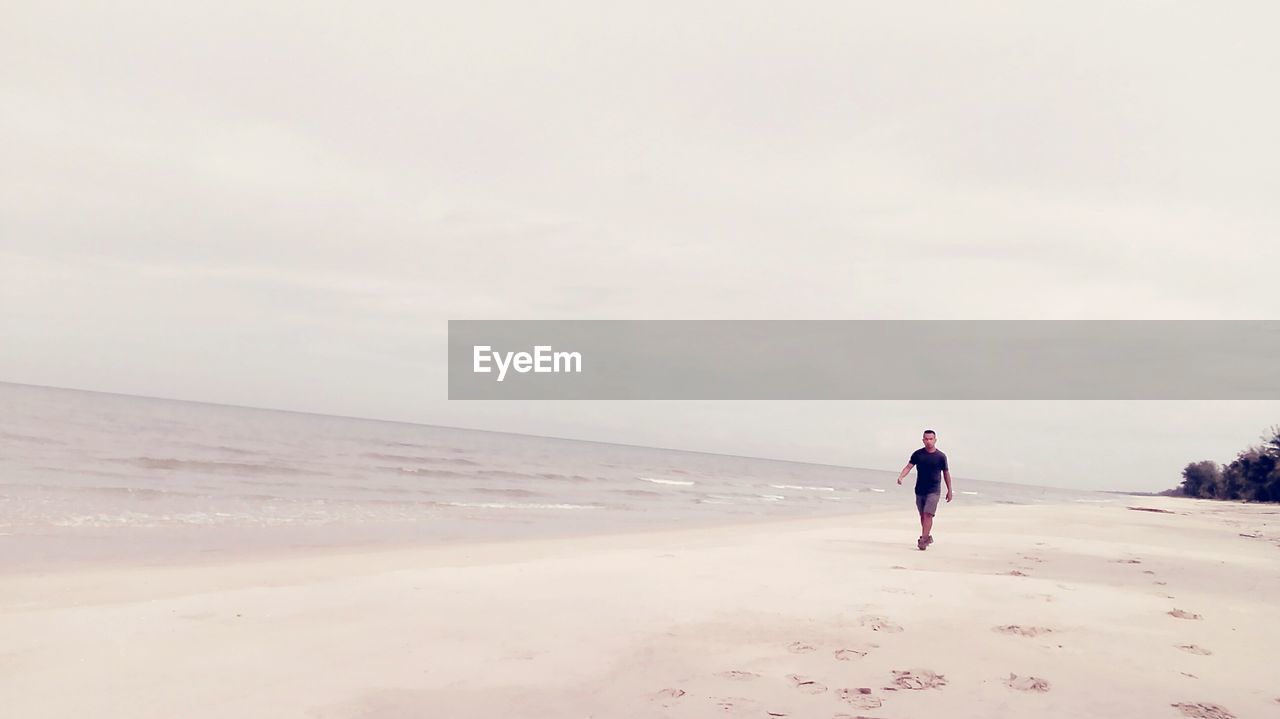 Full length of man walking at beach against sky