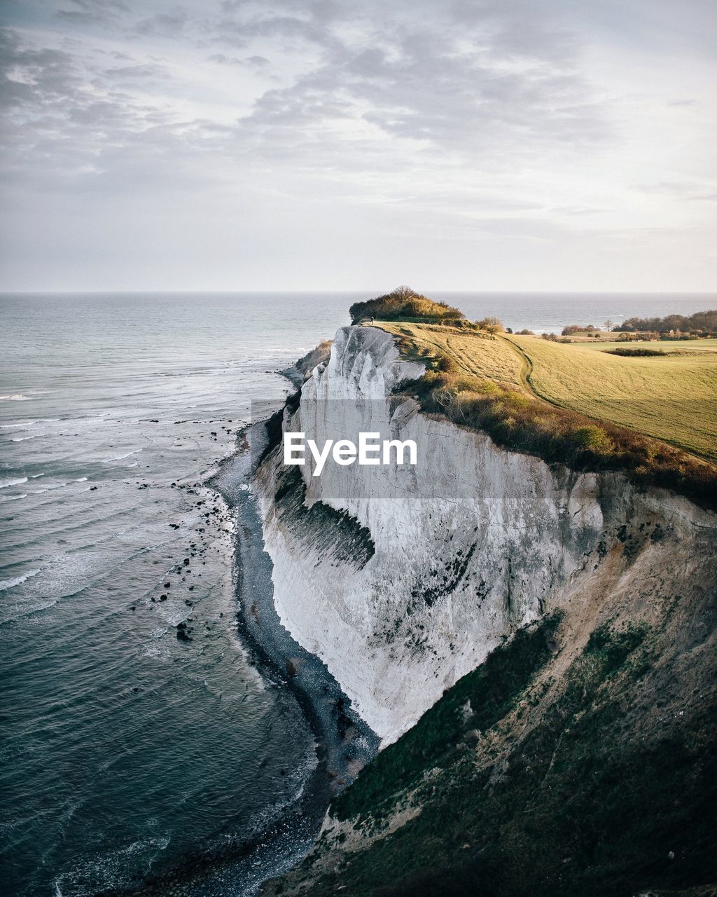 Scenic view of sea by mountain against sky