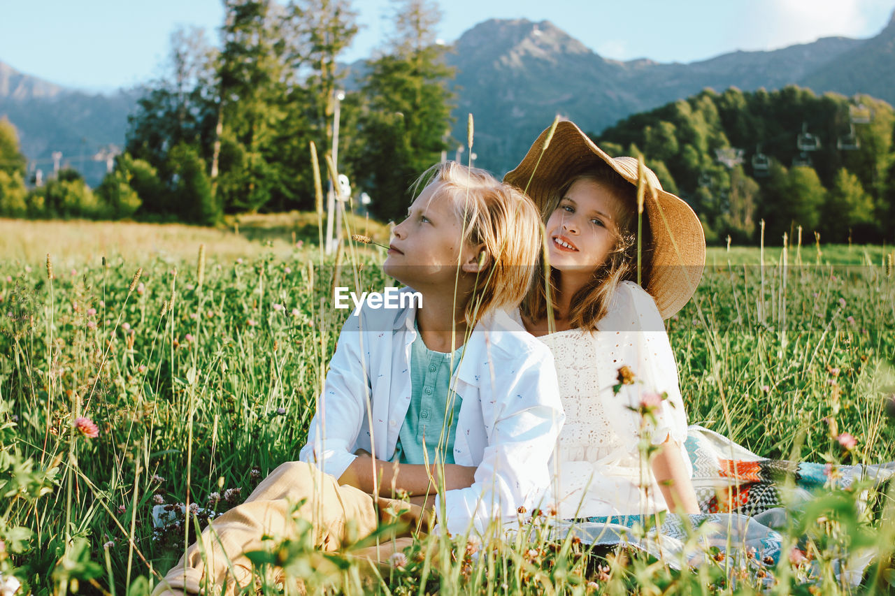 Siblings sitting on field