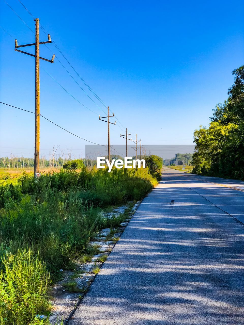 ROAD BY ELECTRICITY PYLON AGAINST SKY