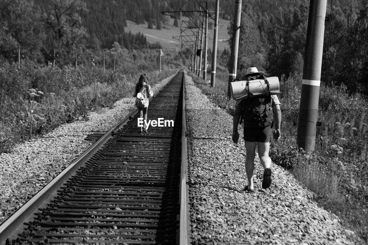 Rear view of people hiking by railroad tracks