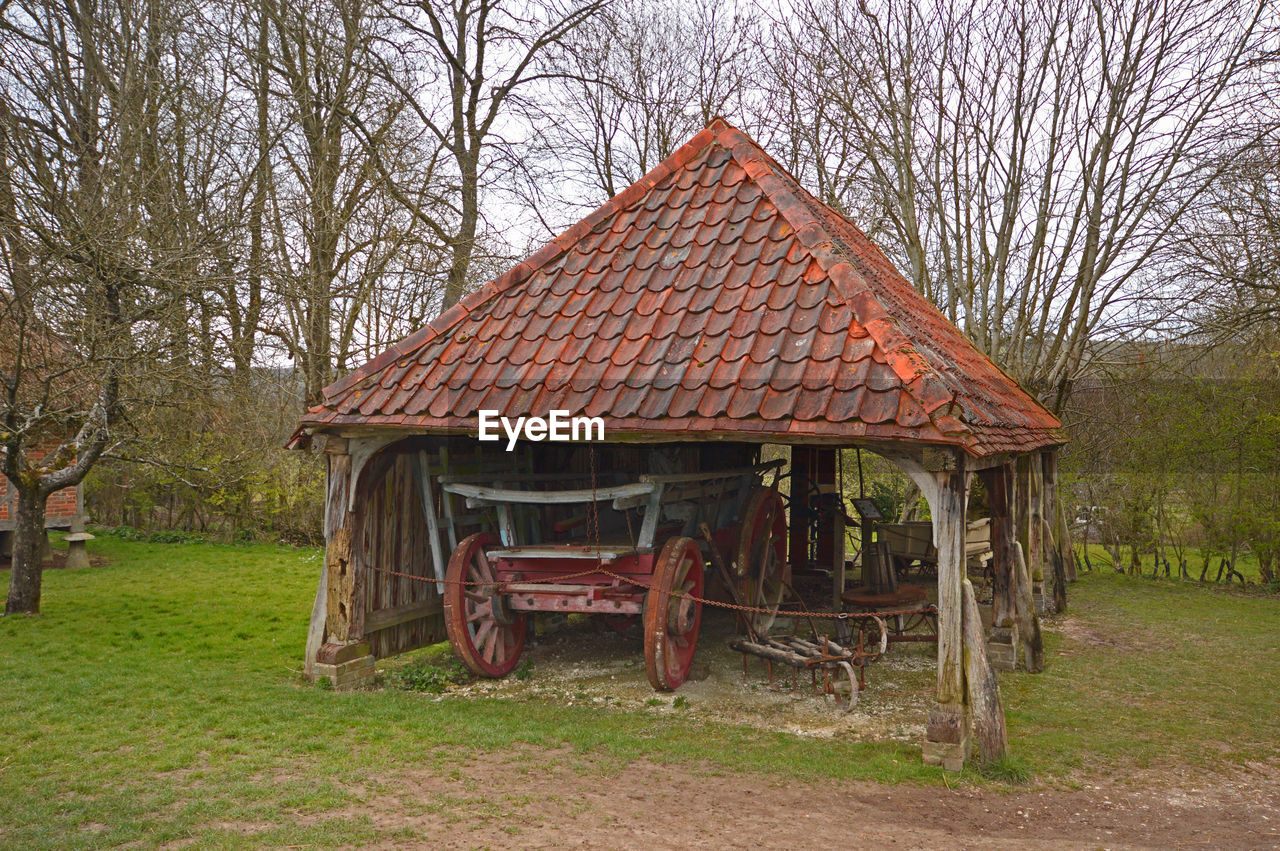 OLD HOUSE ON FIELD AGAINST TREES AND PLANTS