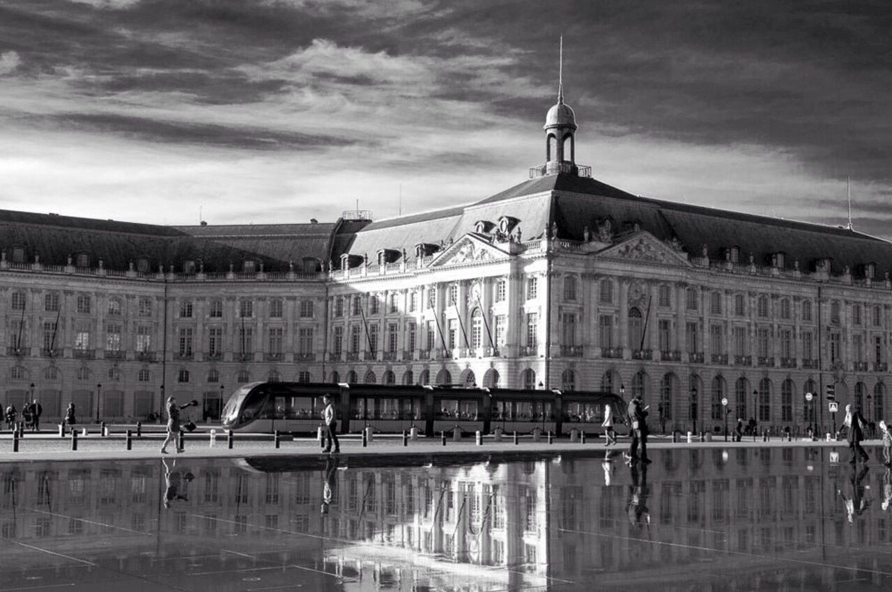 Tram in front of building with reflection in lake