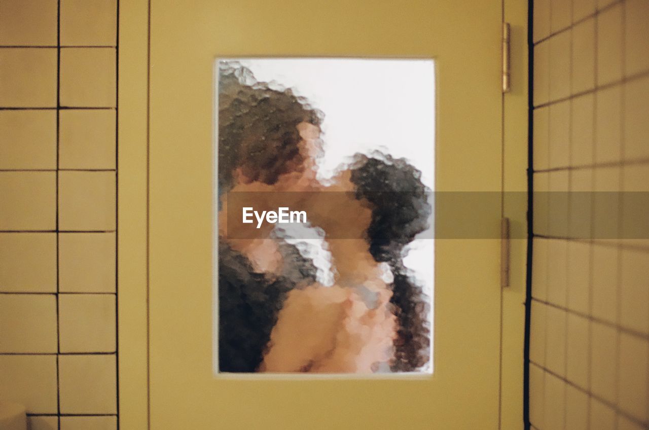 Couple kissing on the mouth seen through glass door