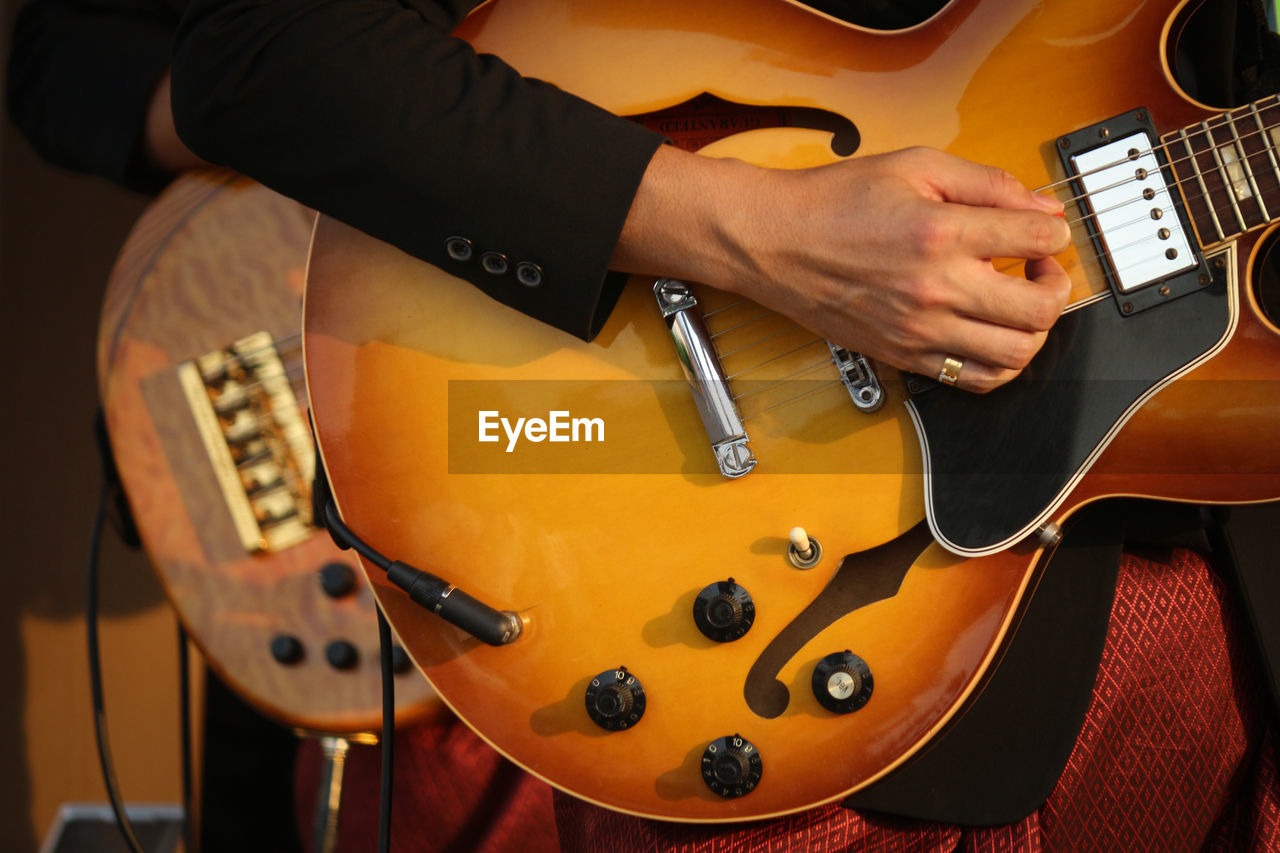 Midsection of man playing guitar in music concert