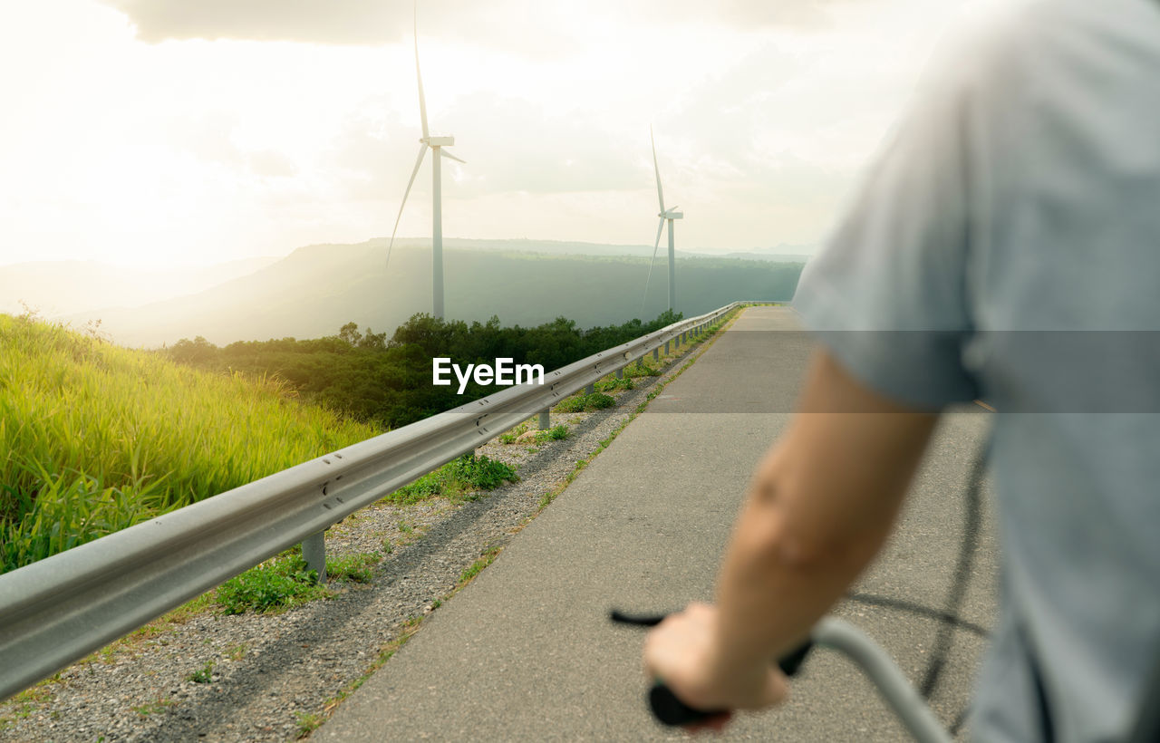 Selective focus on wind farm with rearview of person riding a bicycle as foreground. wind energy. 