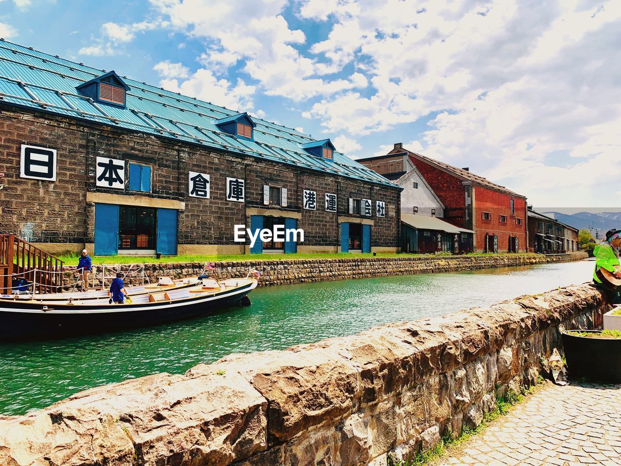 Buildings by canal against sky in city
