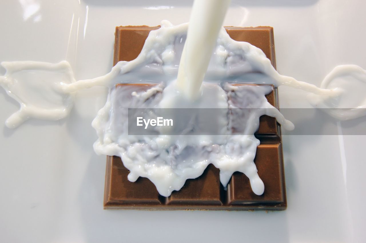 High angle view of milk pouring on chocolate