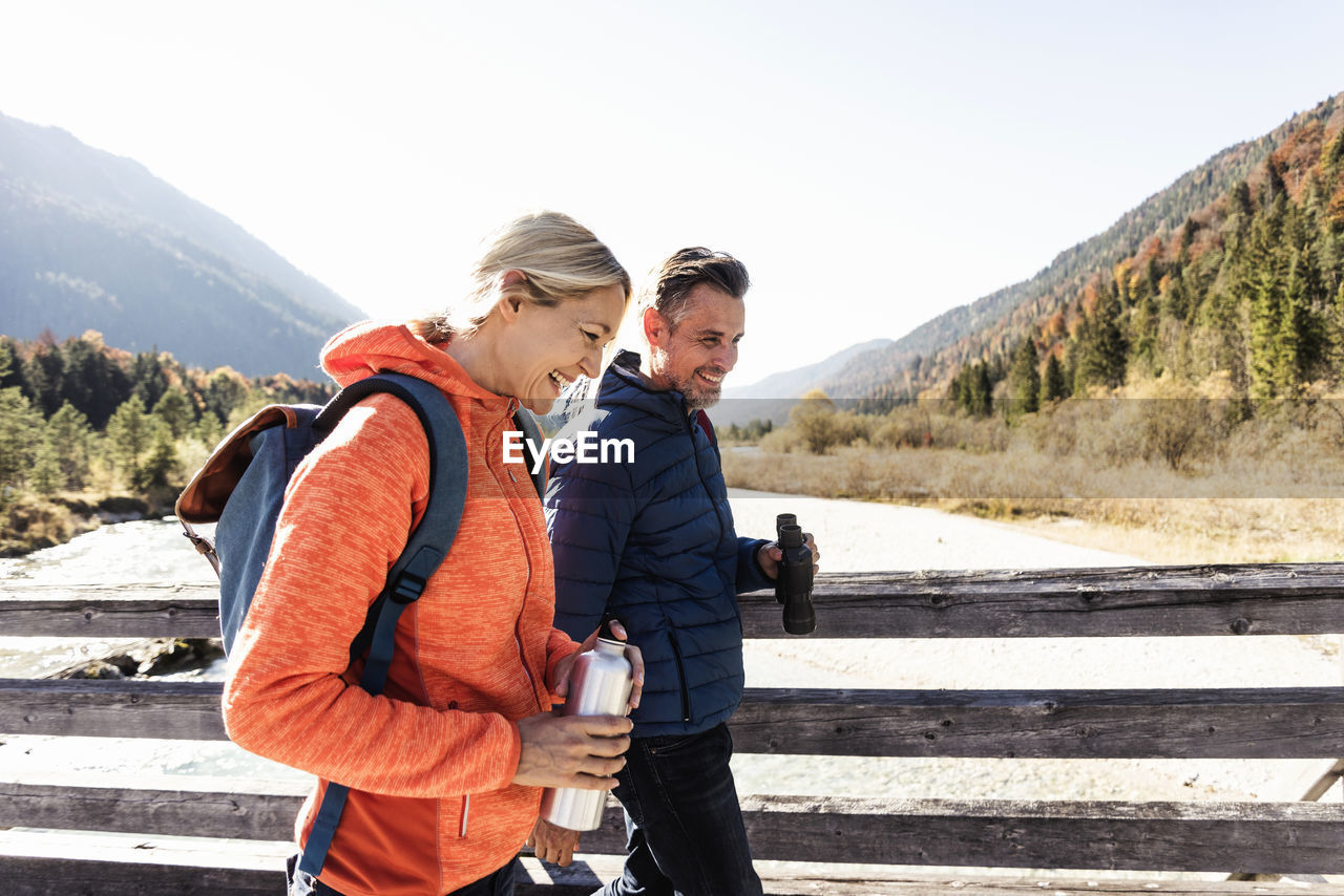 Austria, alps, happy couple on a hiking trip crossing a bridge