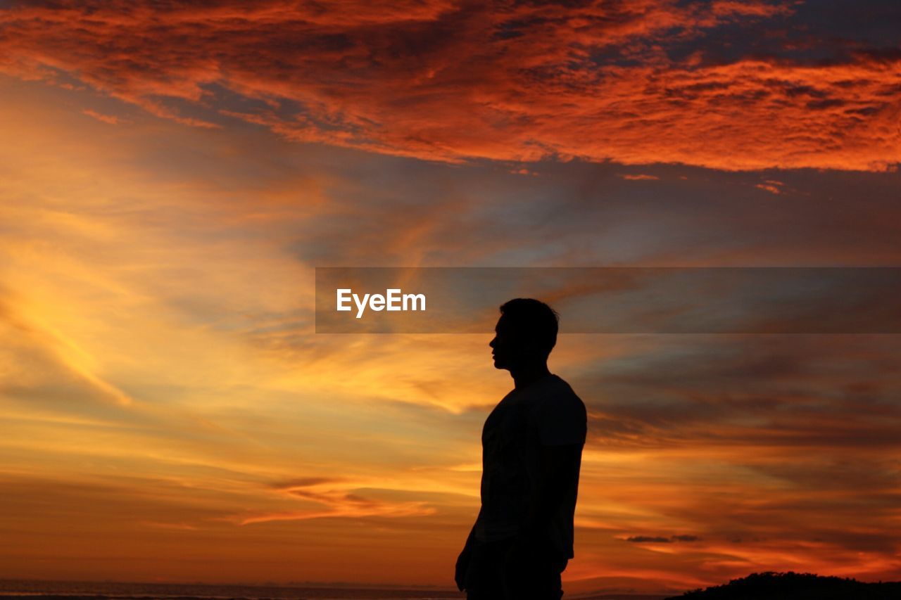 Silhouette man standing against orange sky