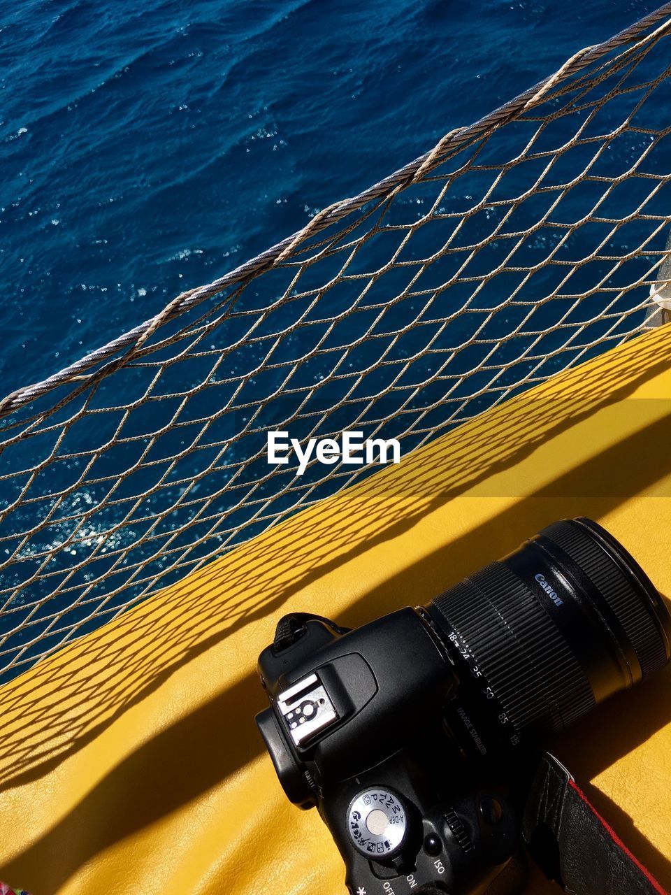 CLOSE-UP OF YELLOW CAMERA AT SEA