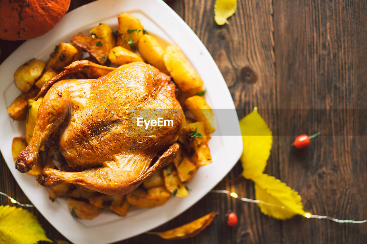 Autumn composition with leaves, ripe pumpkin and thanksgiving turkey on a dark wooden table.