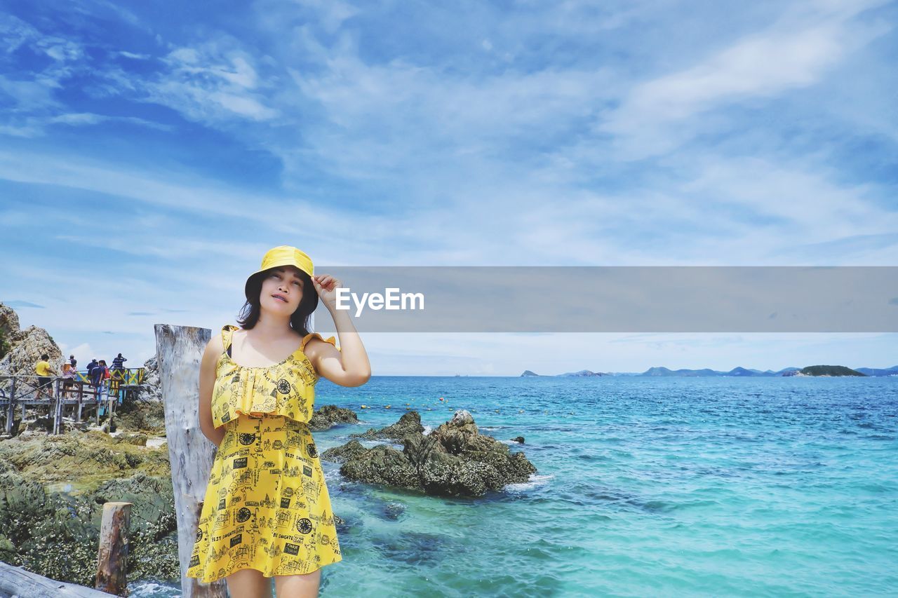 Young woman standing on beach against sky