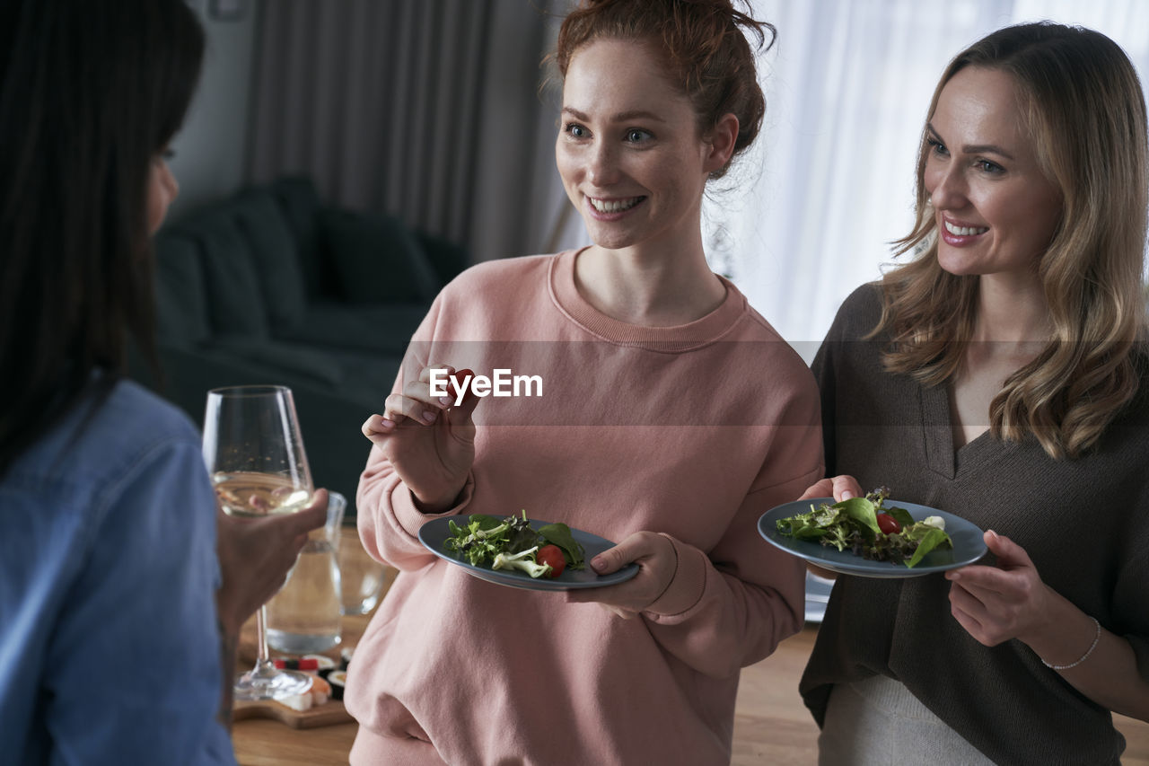 Smiling friends eating food while talking