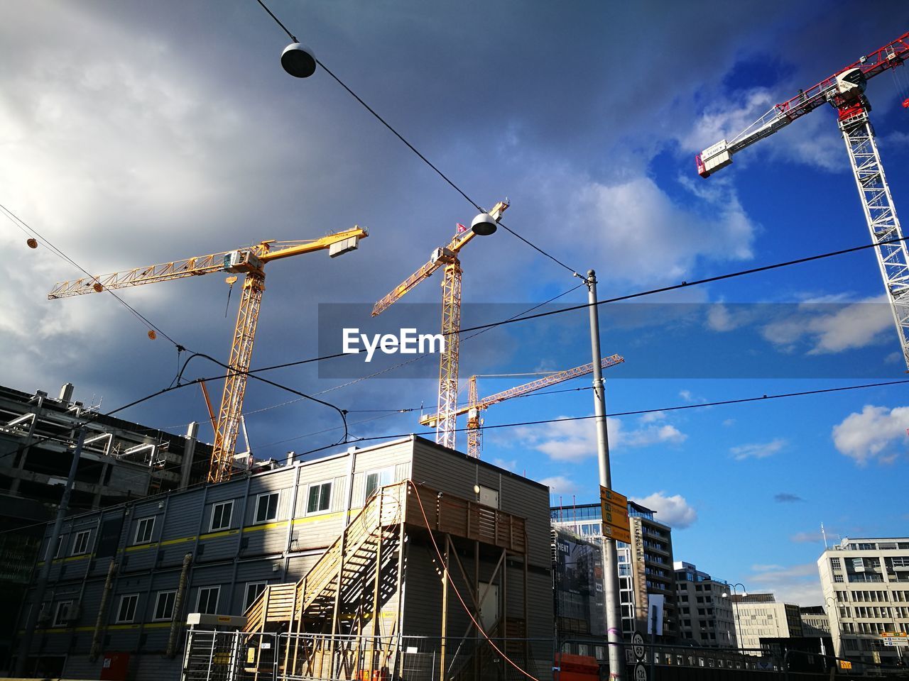 Low angle view of crane by building against sky