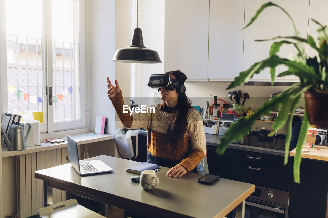 Woman gesturing wearing virtual reality headset at home