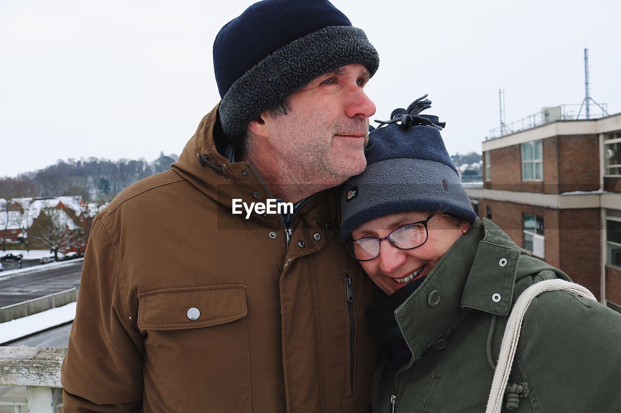 Happy couple against buildings in city at winter