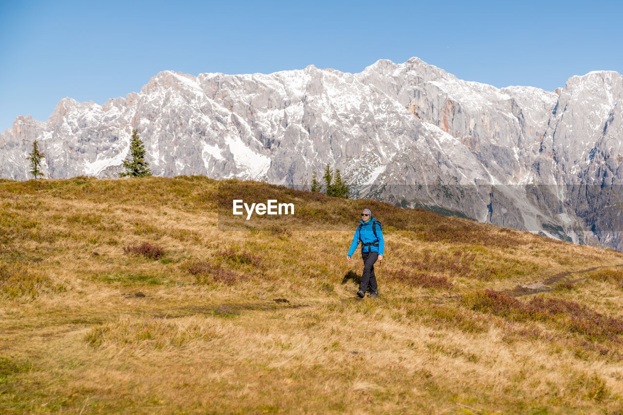 Woman hiking on footpath in alpine landscape, hochkönig, austria.