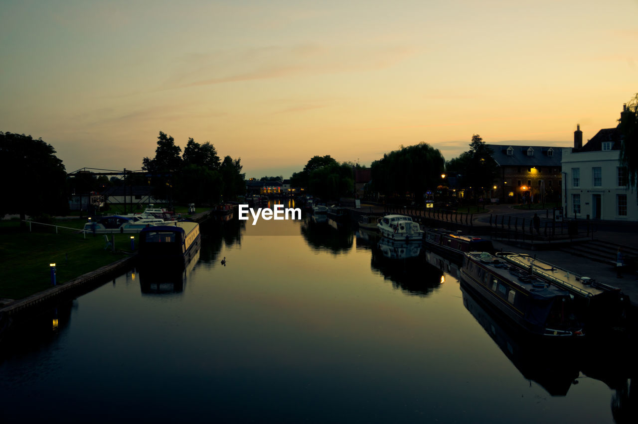 BOATS MOORED IN RIVER DURING SUNSET