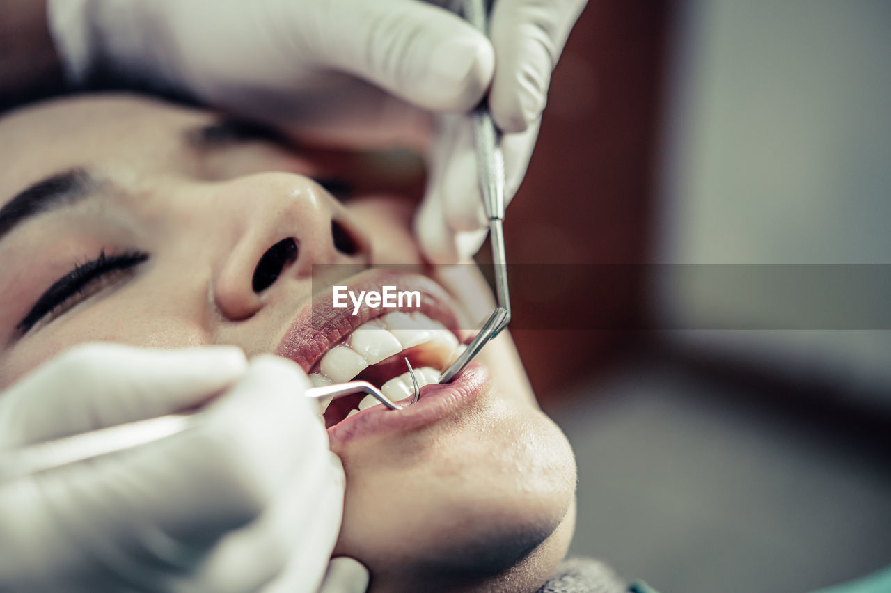 Close-up of young woman getting her teeth examined by dentist