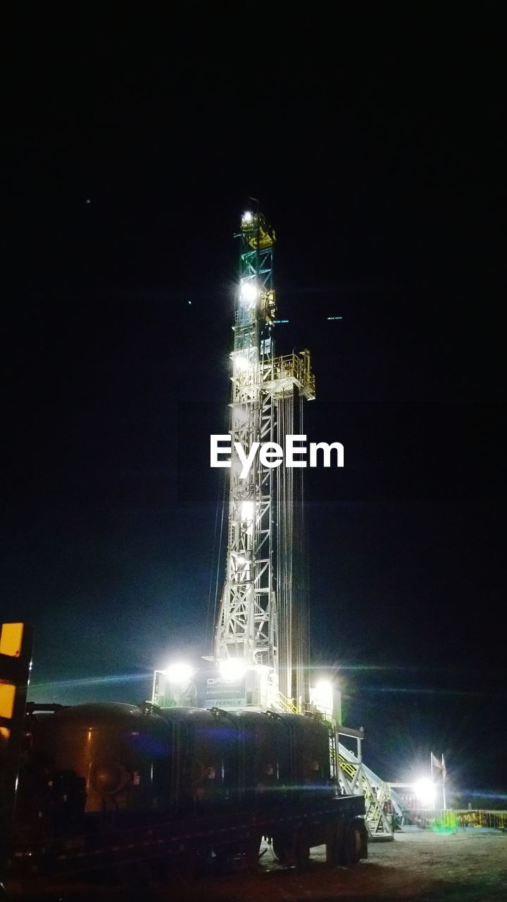 LOW ANGLE VIEW OF ILLUMINATED FERRIS WHEEL AT NIGHT