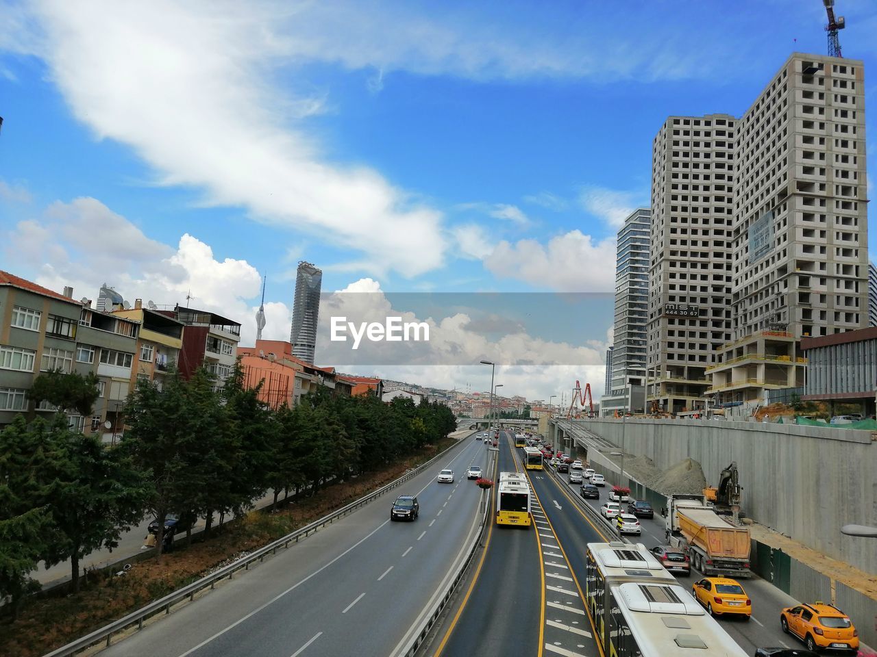 VEHICLES ON ROAD AMIDST BUILDINGS AGAINST SKY