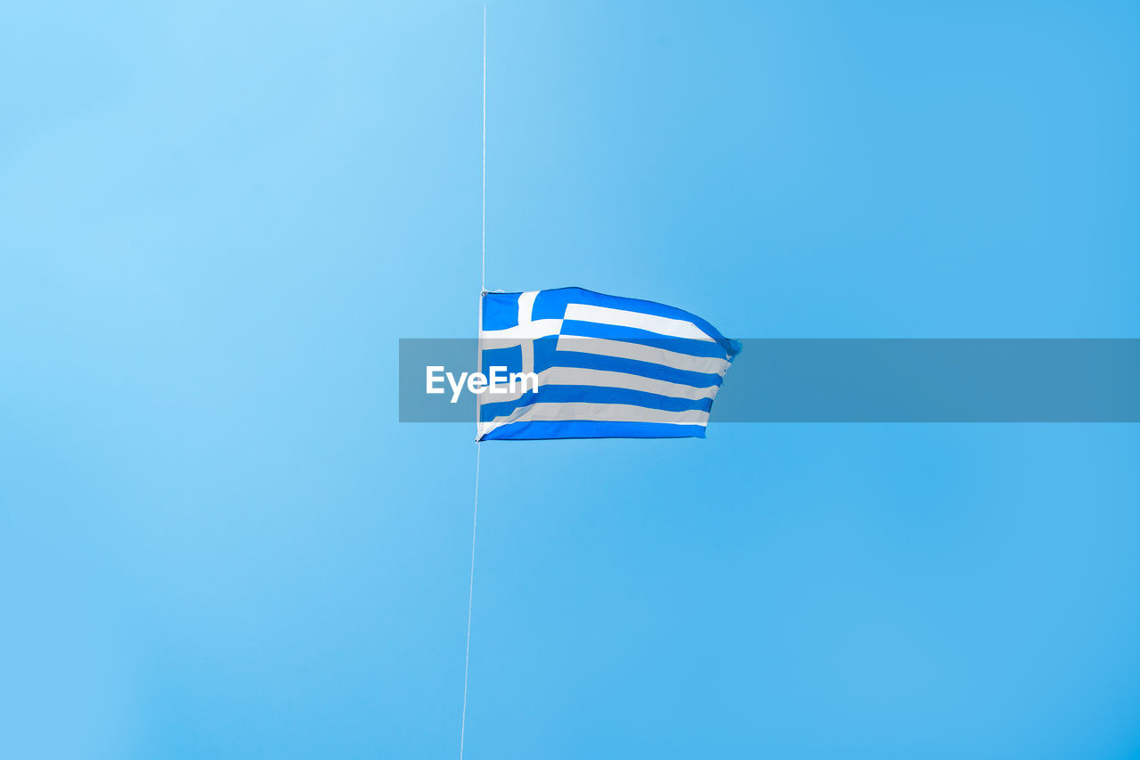 Low angle view of flag against clear blue sky