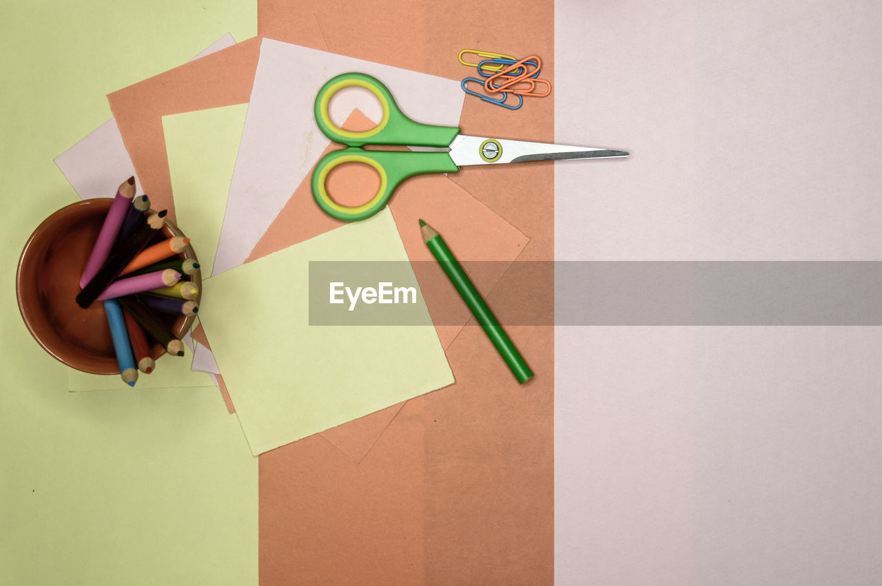 Colour paper, scissors, pencils, paint on table. origami diy tutorial for kids background. 