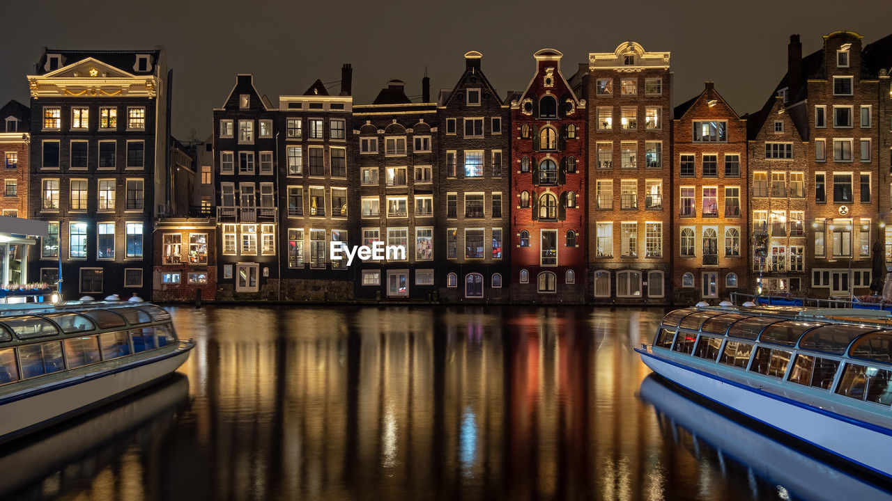 Medieval houses and cruise boats at the damrak in amsterdam the netherlands by night