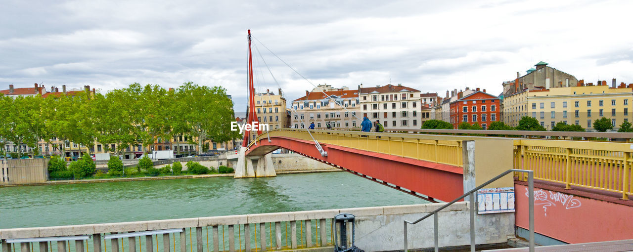 ARCH BRIDGE OVER RIVER AMIDST BUILDINGS AGAINST SKY