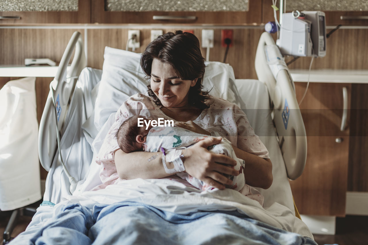 Mid view of mother in hospital bed looking at newborn son