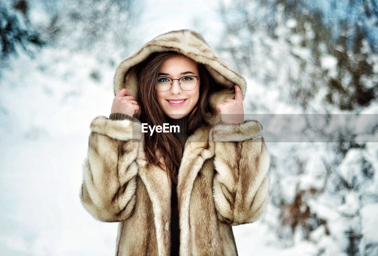 Portrait of smiling young woman wearing fur coat during winter