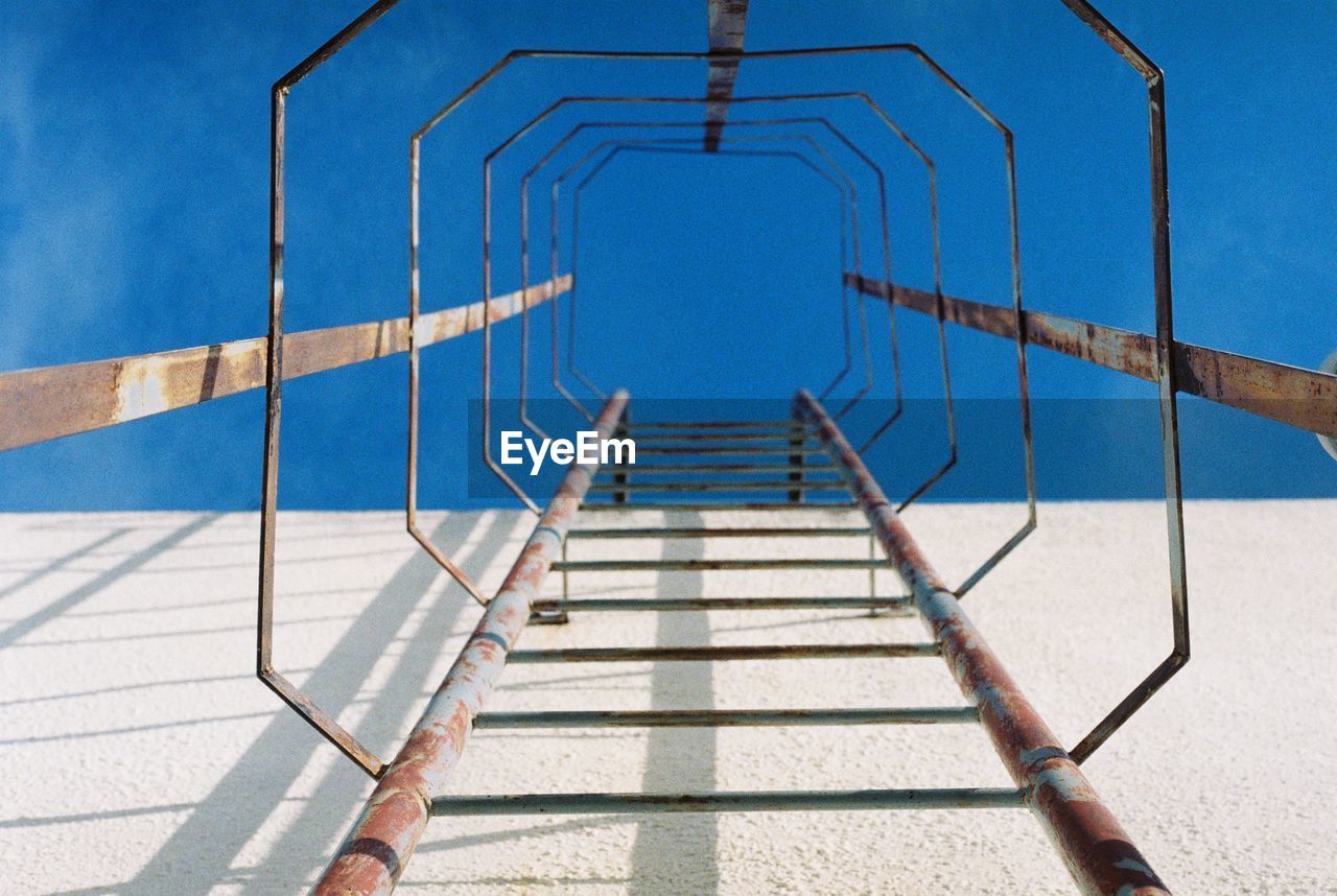 Low angle view of ladder against blue sky