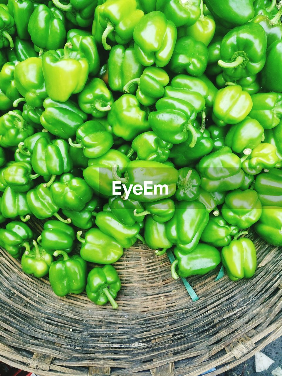 High angle view of green bell peppers in wicker basket for sale