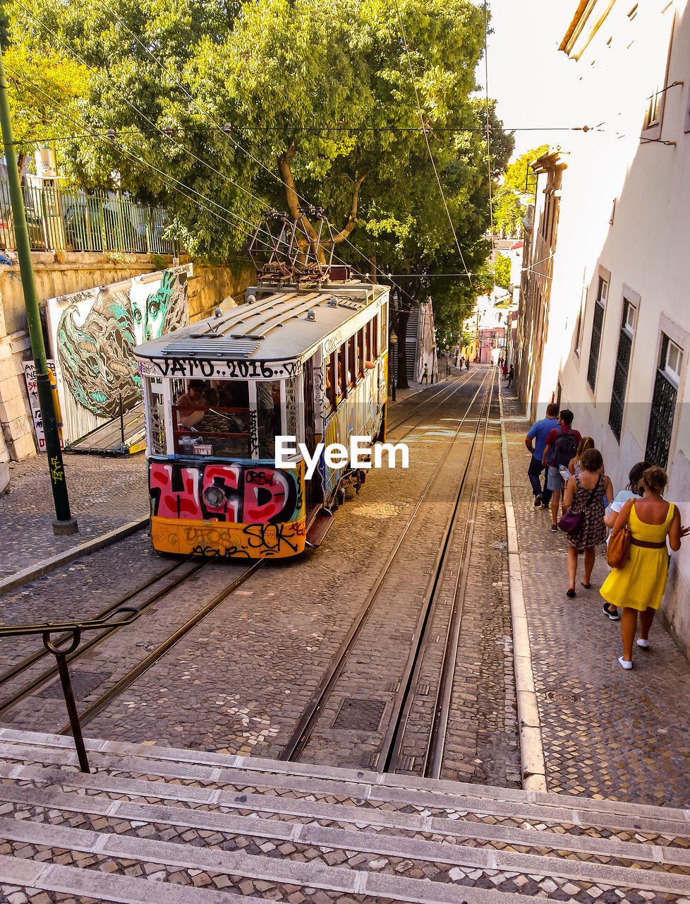 High angle view of people walking on sidewalk with tram on street in city