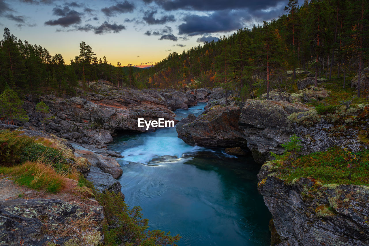 high angle view of river amidst trees against sky during sunset