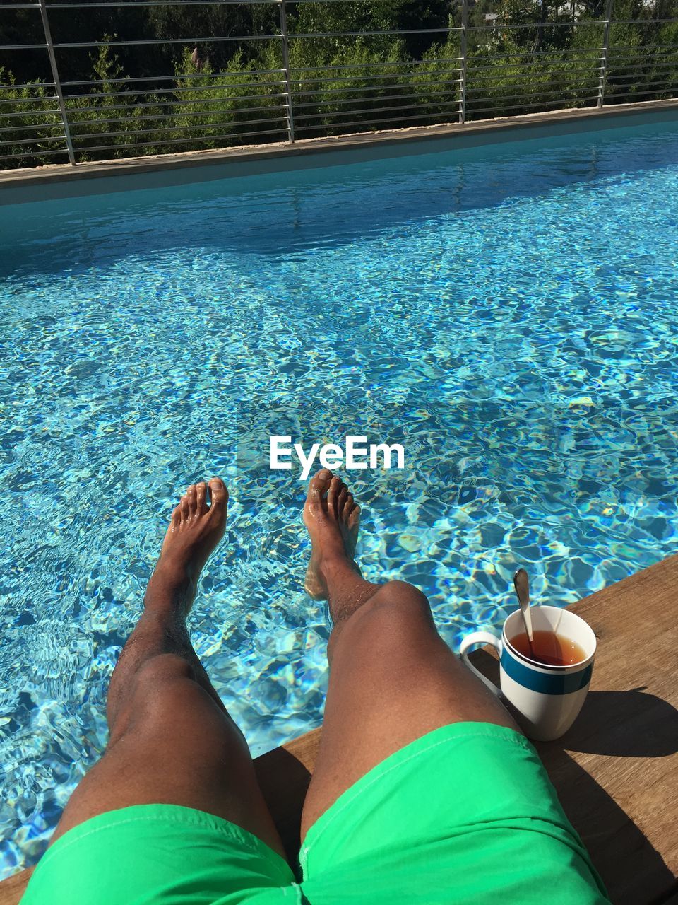 Low section of person with black coffee at poolside