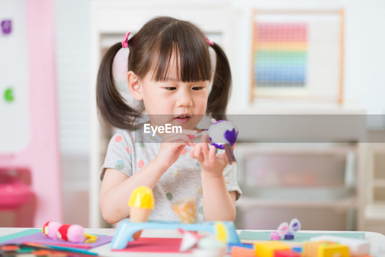 Young girl decorating hand made craft for homeschooling