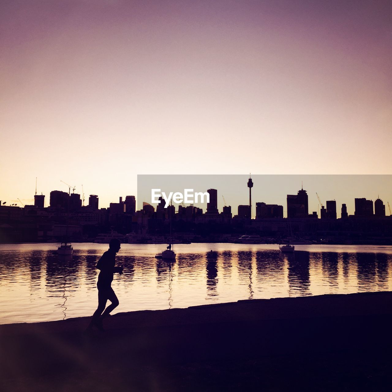 Man running by river against urban skyline