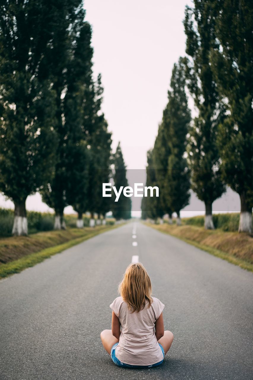 Rear view of girl sitting on road