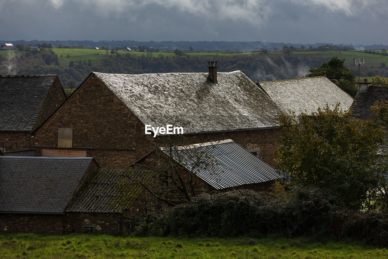 architecture, rural area, built structure, roof, building exterior, house, building, sky, cloud, nature, farm, environment, landscape, plant, rural scene, residential district, land, hill, no people, agriculture, thatching, outdoors, field, grass, village, environmental conservation, day, history, tree