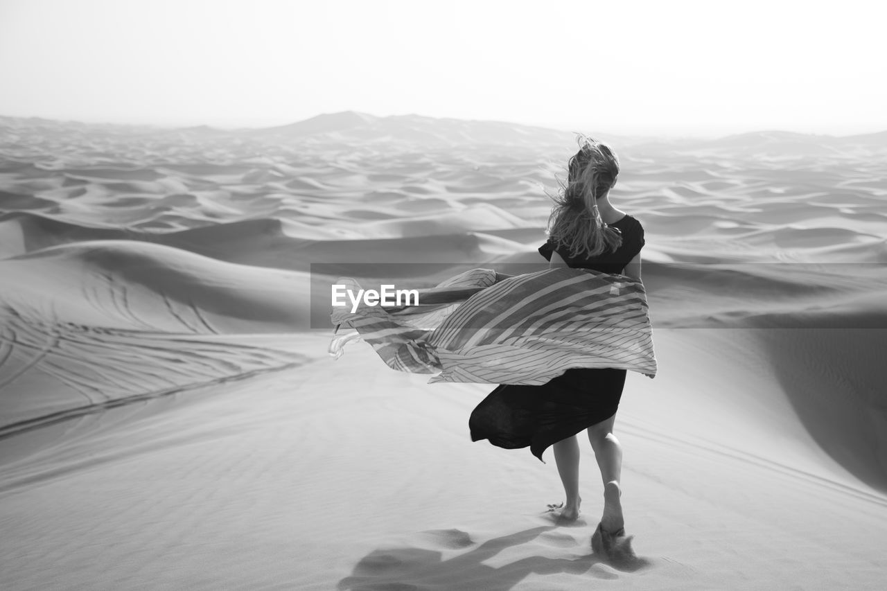 Rear view of woman walking in sea against sky