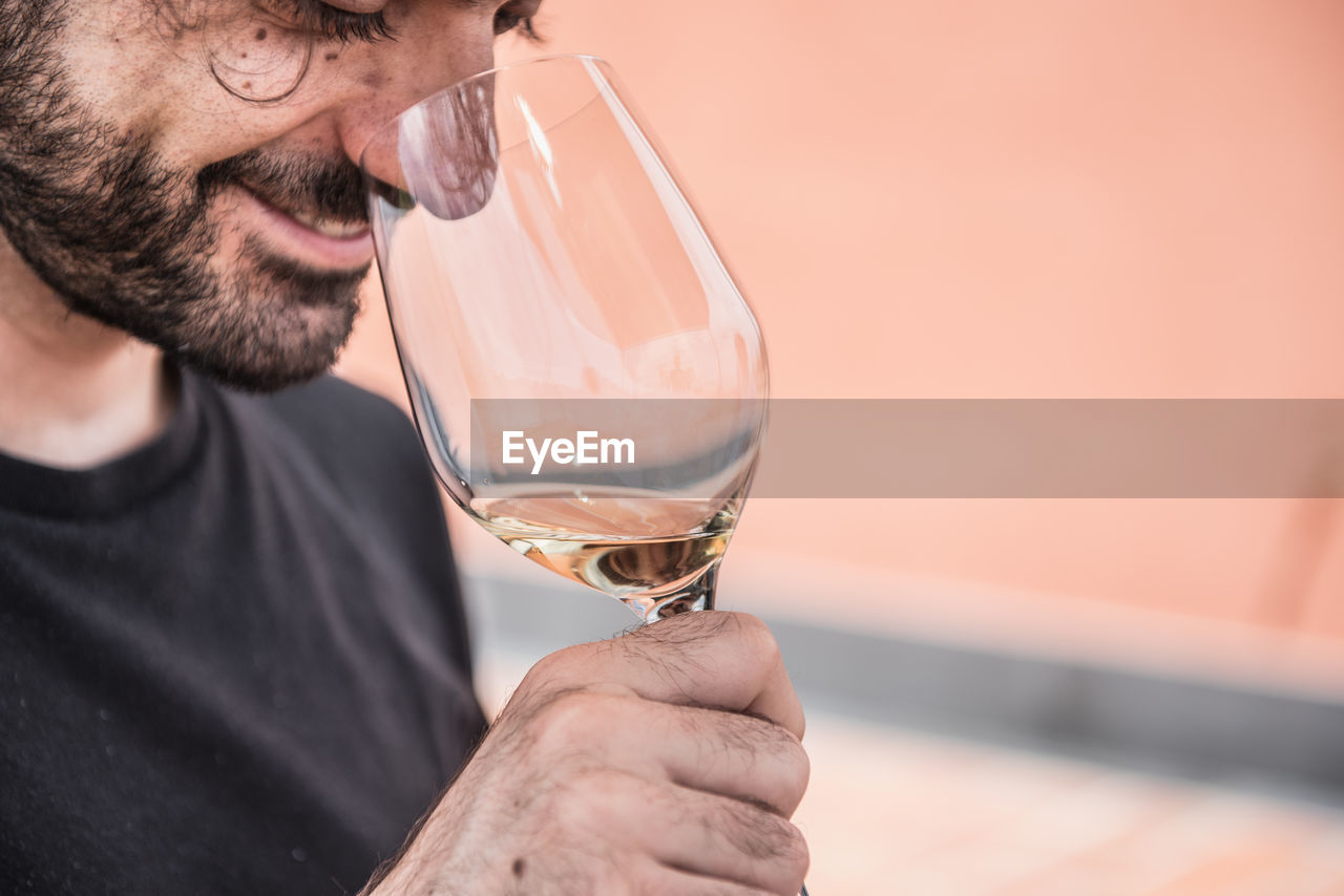 Close-up of smiling man smelling wine