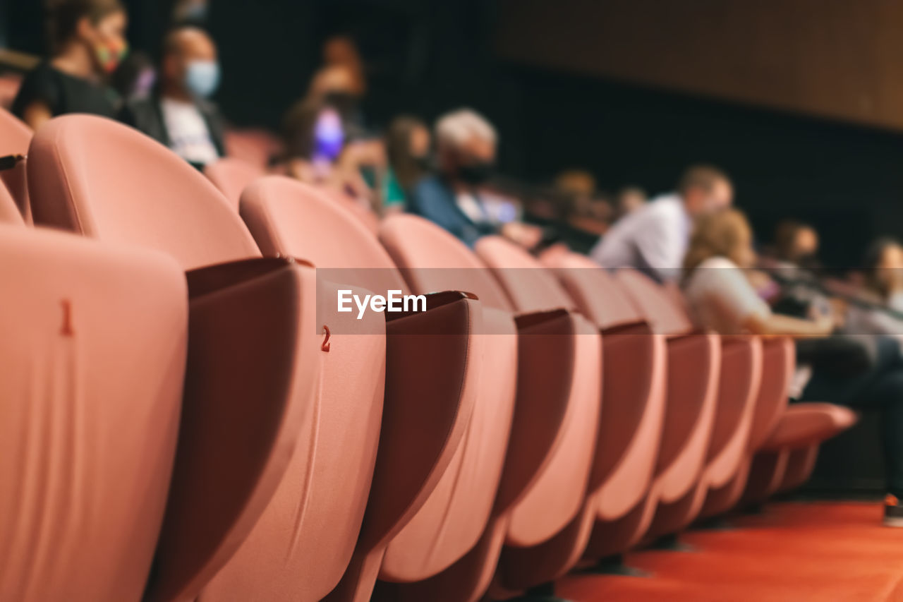 in a row, group of people, crowd, auditorium, audience, indoors, seat, adult, large group of people, sports, arts culture and entertainment, men, focus on foreground, movie theater