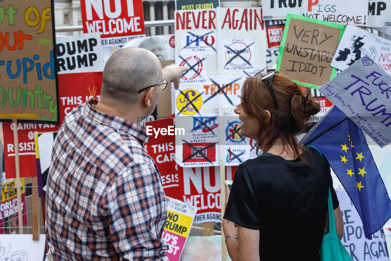 REAR VIEW OF A COUPLE STANDING AGAINST GRAFFITI