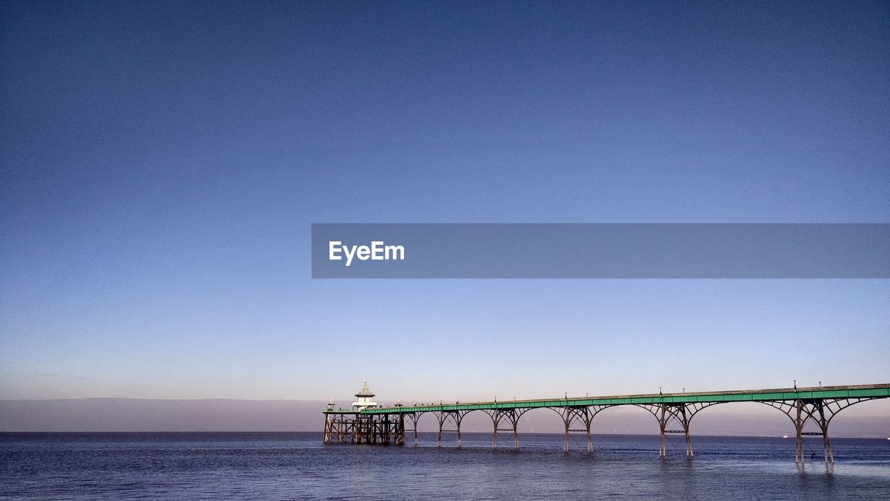 Scenic view of bridge over sea against clear blue sky