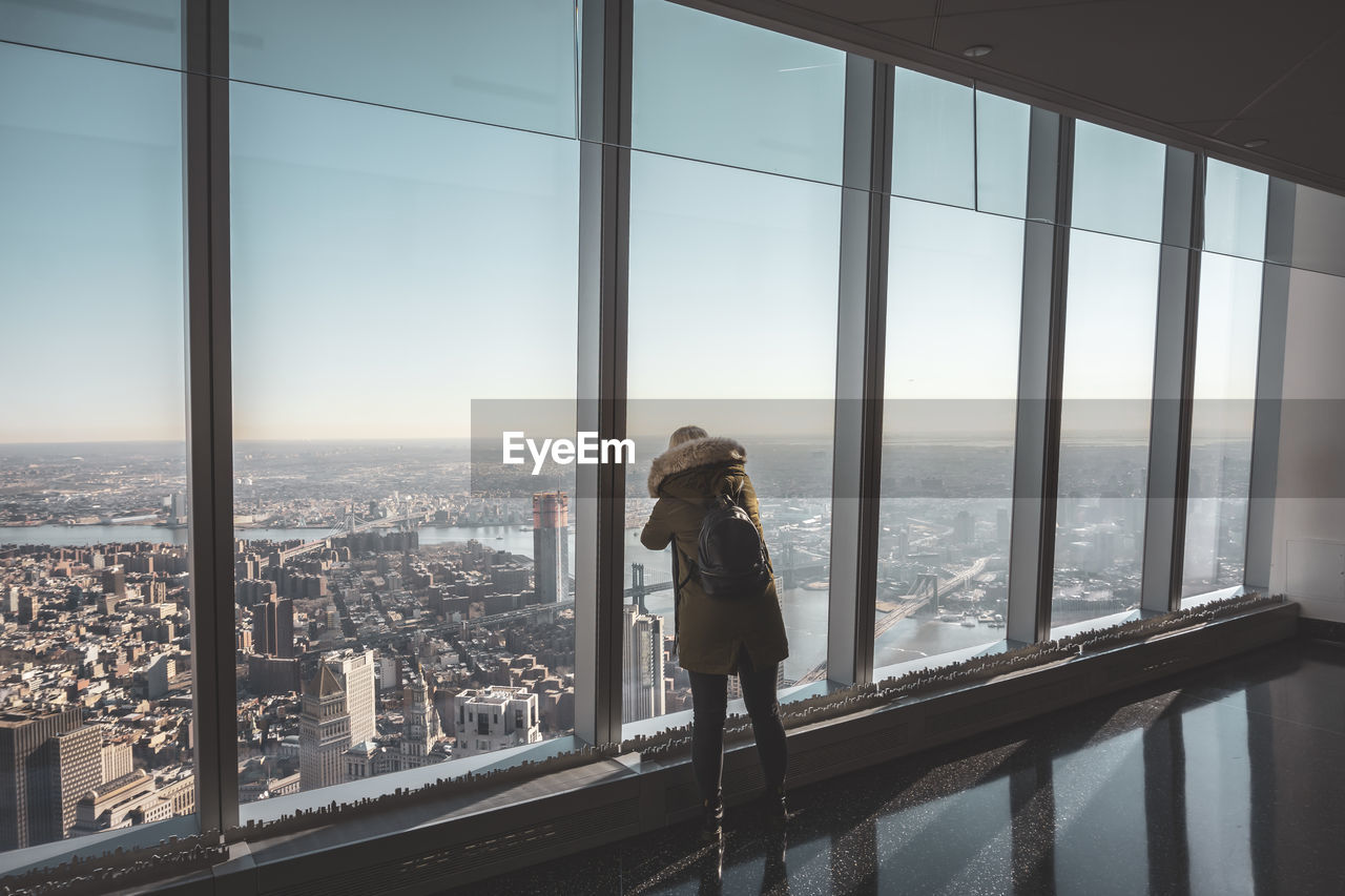 MAN LOOKING THROUGH WINDOW IN CITY BUILDING