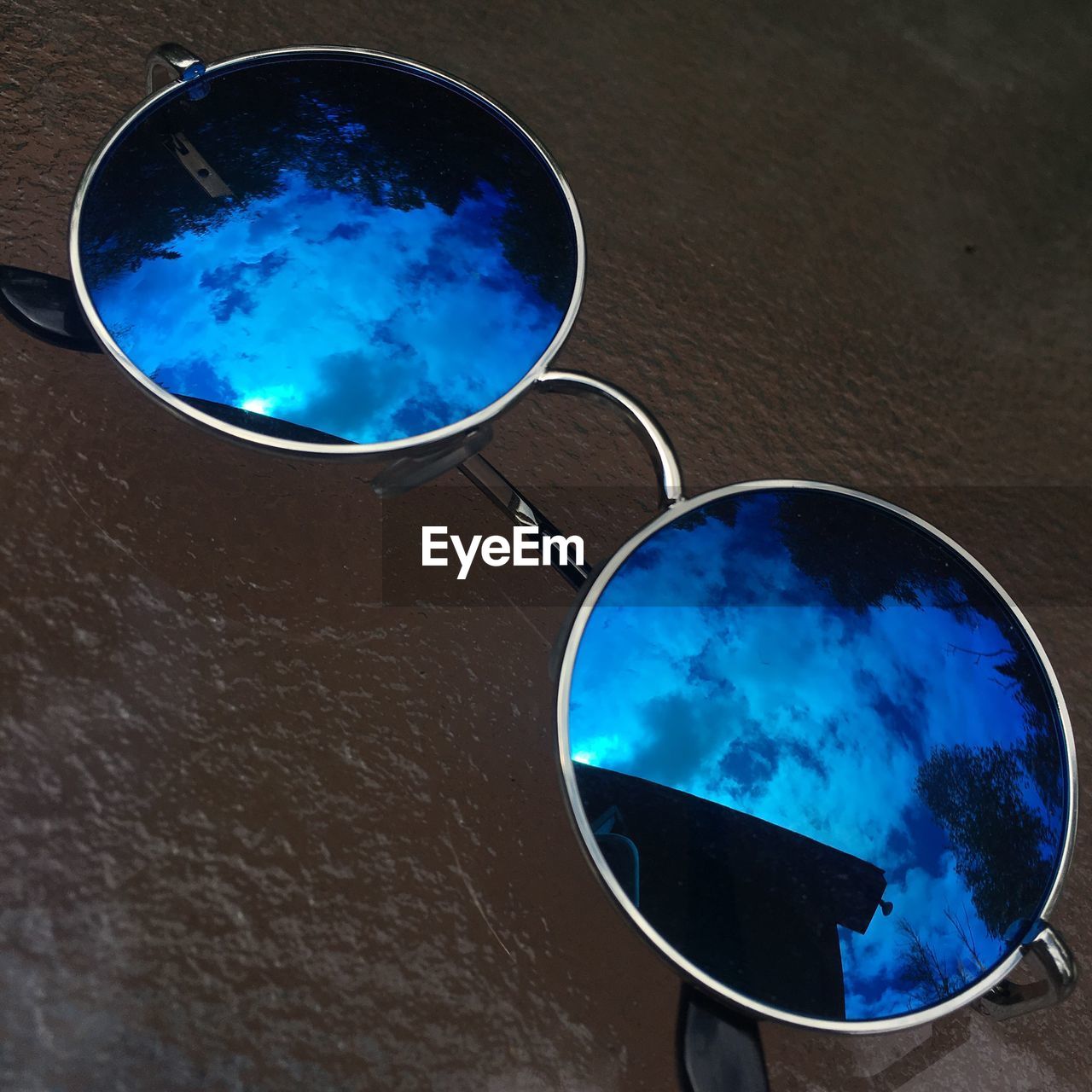 REFLECTION OF SUNGLASSES AND BLUE SKY ON MIRROR
