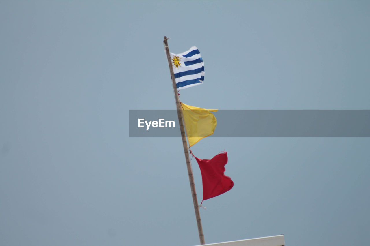 LOW ANGLE VIEW OF FLAGS AGAINST CLEAR SKY