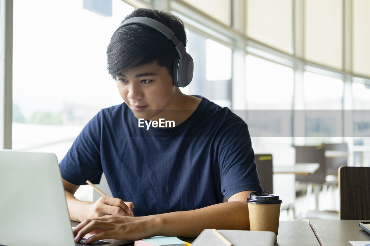 Young collage student using computer and mobile device studying